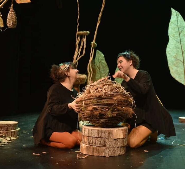 Les deux comédiennes sont à genoux autour d'un nid géant.