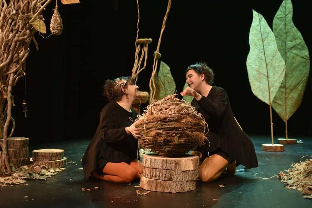 Les deux comédiennes sont à genoux autour d'un nid géant.