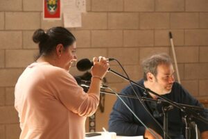 Une femme est devant un micro pour enregistrer sa voix.