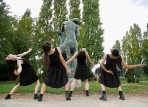 4 danseuses de dos, penchées en arrière, dans un jardin autour d'une statue de centaure.