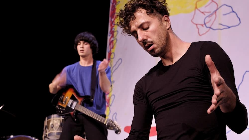 Le danseur et chorégraphe Laurent Cebe en gros plan et le musicien Jonathan Poulet avec sa guitare électrique en arrière plan.