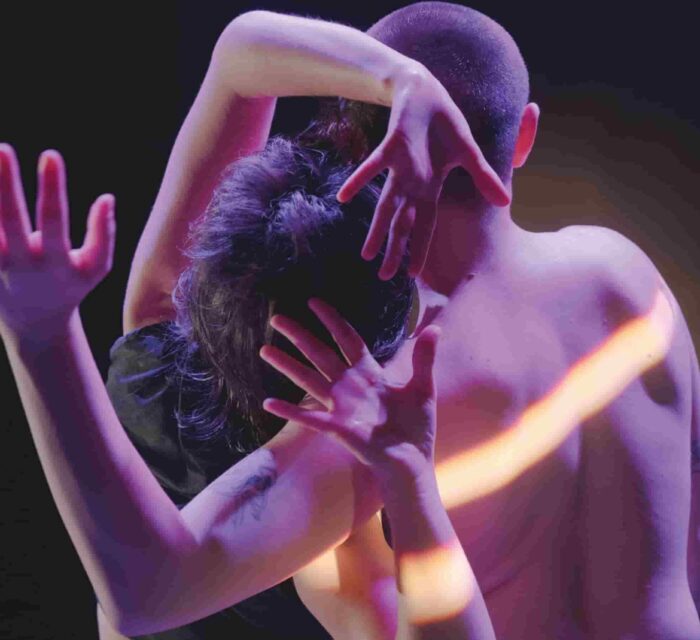 Cadrage serré sur le haut du corps de deux interprètes, de dos.