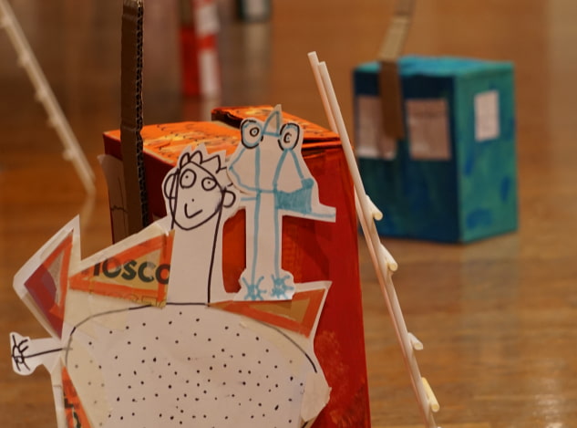 Figurines de papier et maison de carton créées au cours d'un atelier.