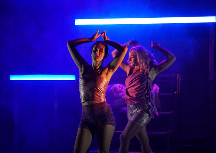 Une jeune femme danse les bras en l'air et les yeux fermés dans une lumière bleutée. Un deuxième personnage apparaît en arrière plan, habillé de la même manière, comme son double.